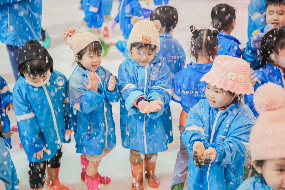Các bé đang vui vẻ trượt tuyết trên máng trượt tại Snow Town Sài Gòn, một khu vui chơi có tuyết thật độc đáo ở Quận 2.
