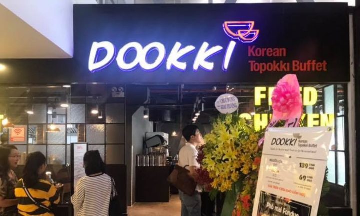 Không gian bên trong Dookki Vincom Phan Văn Trị với các bàn ăn và quầy line buffet, thể hiện rõ hình ảnh của Dookki Vincom Phan Văn Trị hiện đại và sạch sẽ.