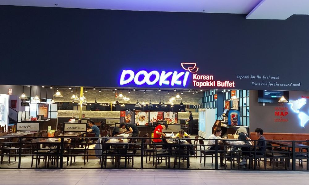 Không gian Dookki Quang Trung ấm cúng với dãy bàn ghế và quầy buffet đa dạng, mang đến cảm giác thoải mái cho thực khách muốn khám phá ẩm thực Dookki.
