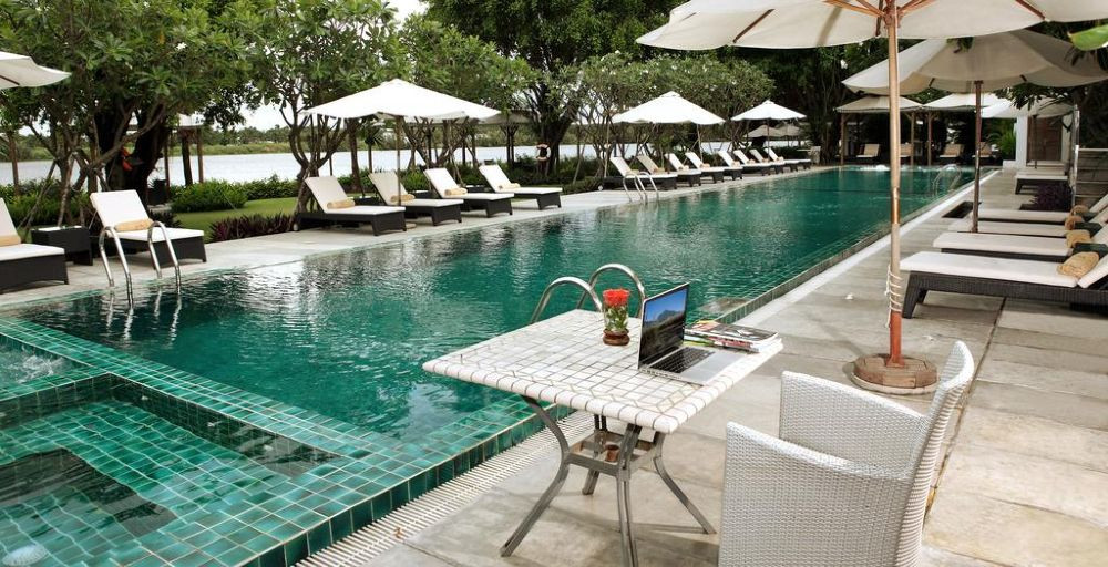 Một bể bơi ngoài trời sang trọng tại Thảo Điền Village, với khung cảnh cây xanh và dòng sông Sài Gòn thơ mộng, mang đến cảm giác thư giãn cho du khách.