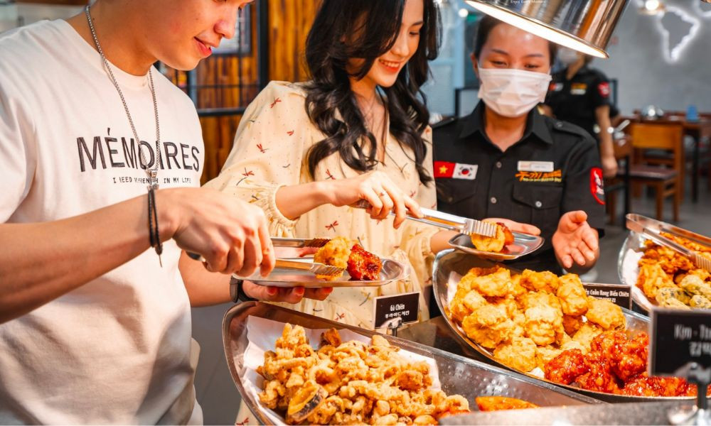 Nhân viên Dookki đang phục vụ và hỗ trợ khách hàng tại quầy buffet, thể hiện dịch vụ chuyên nghiệp và tận tâm.